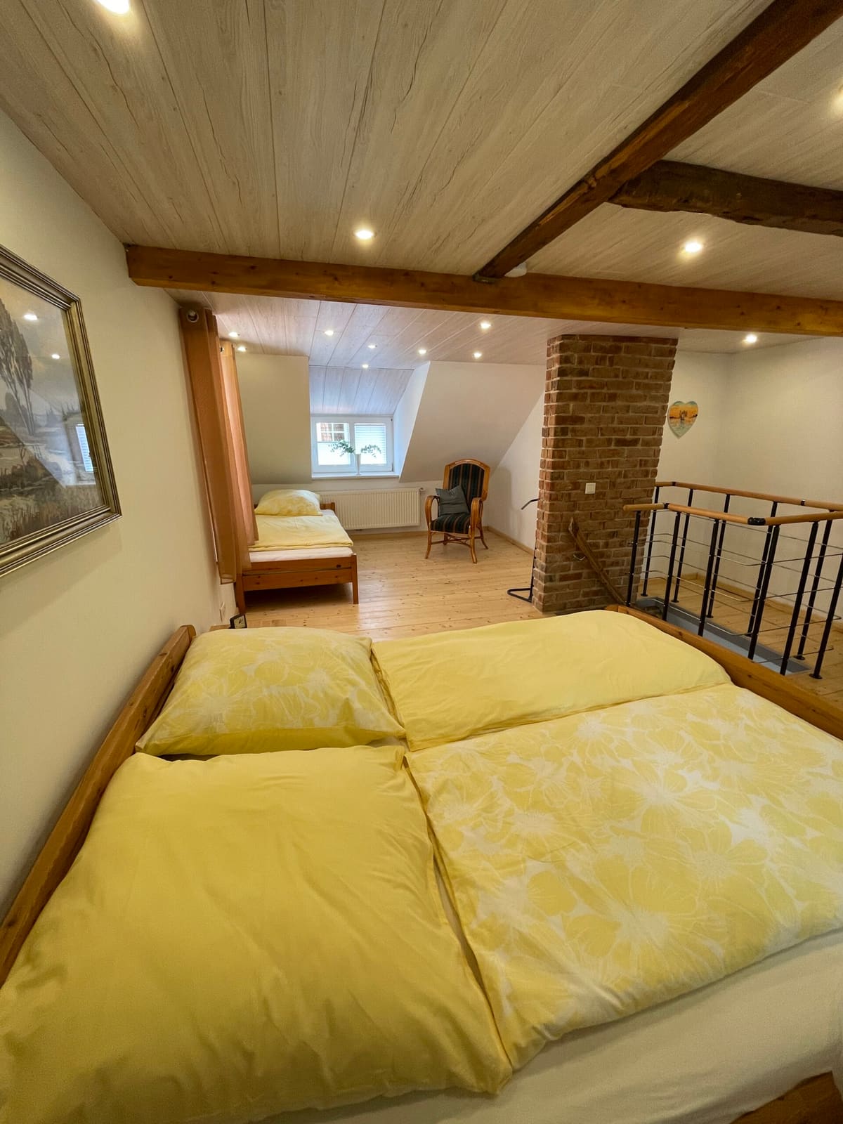 Doppelbett unter Holzbalken im Dachgeschoss des Ferienhauses